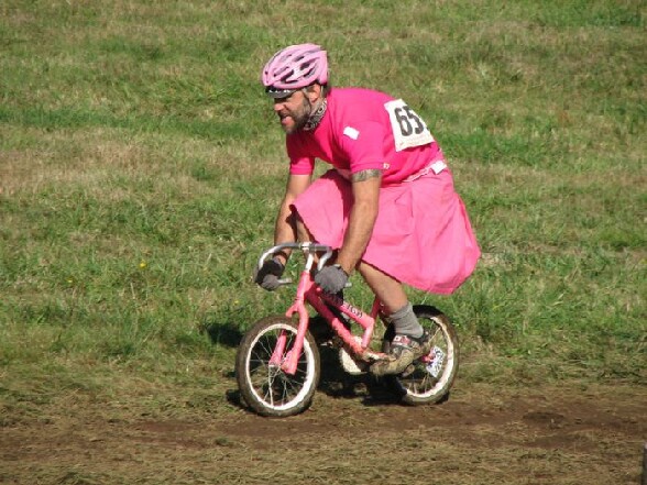 courses-cycliste-insolite-une-mec-plutot-age-fait-du-velo-sur-velo-de-petite-fille-rose-avec-une-robe-rose-aussi